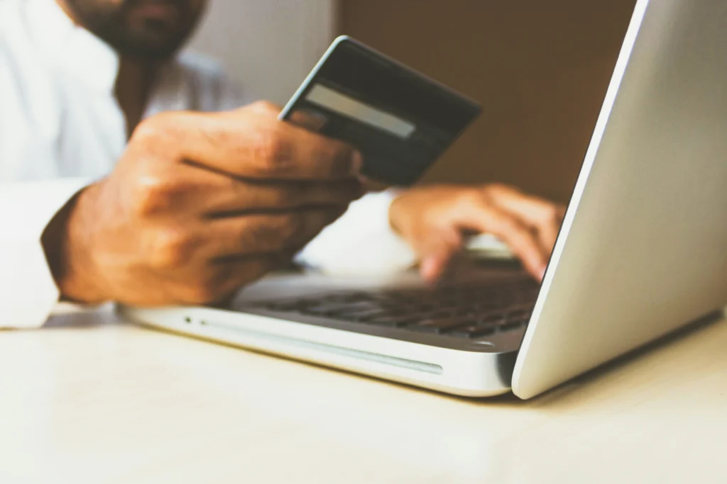 Persoon houdt een creditcard vast en gebruikt een laptop met zachte verlichting in een kantoor omgeving